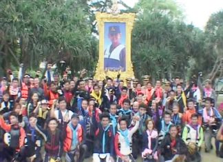 The Jet Ski Riders pose for a photograph under a picture of His Majesty the King